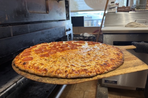 A half cheese, half pepperoni pizza fresh out of the oven in a pizzeria kitchen.