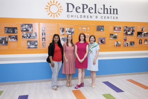 four women stand in front of a DePelchin sign