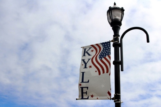 The image shows a lamp post with a banner that says Kyle. The banner also depicts an American flag and an outline of the state of Texas.
