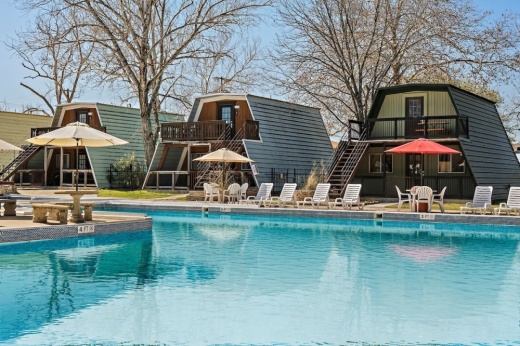 Small cottages situated behind an expansive pool area.