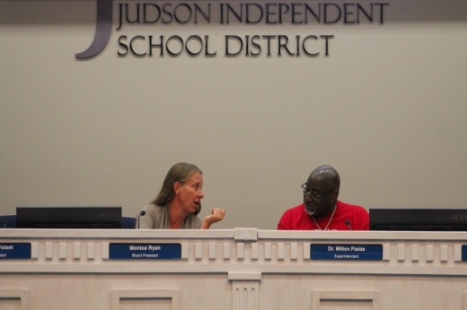 A white female school board president and a black male district superintendent discuss financial matters at administrative offices in Live Oak, Texas.