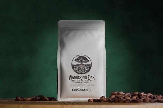 A bag of coffee next to a pile of coffee beans on a wooden table.