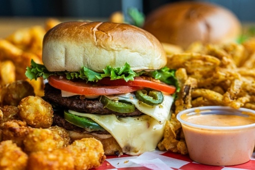 The image shows a plate with tater tots, a cheeseburger and sauce.