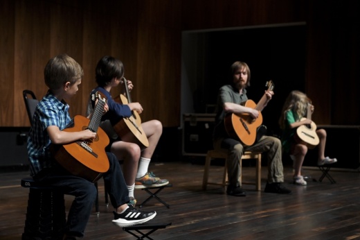 Students play guitars on stage