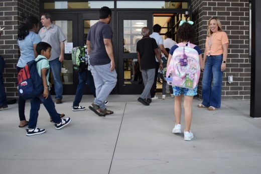 students and their parents walk into an elementary on the first day of school