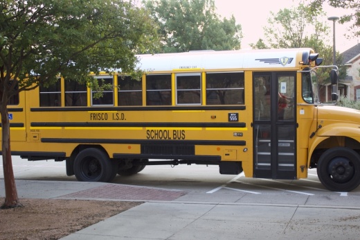 a yellow school bus for Frisco ISD pulls up to an elementary school