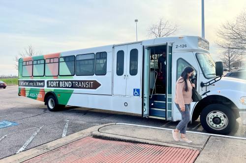 woman gets off of a bus