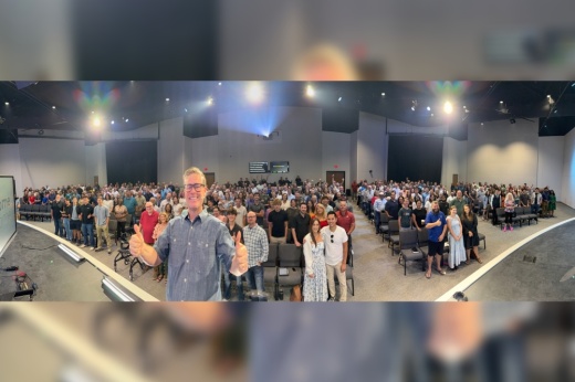 Male in the forefront of an auditorium of people.