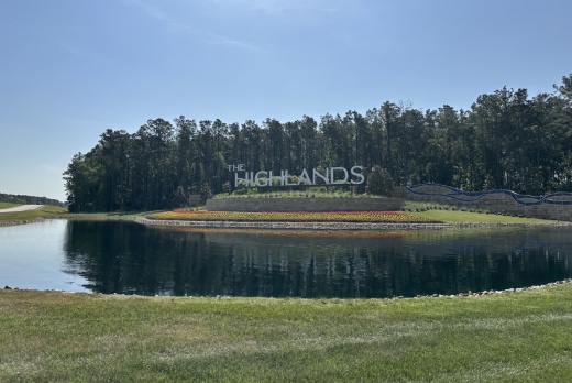 'The Highlands' sign across a lake and near a small forest