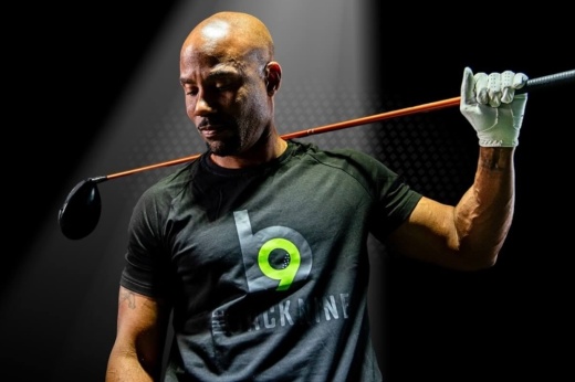 A man holds a golf club over his shoulder getting ready to use a simulator.