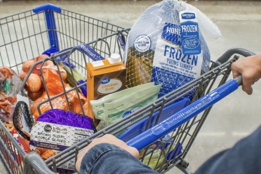 a shopper's grocery cart filled with a frozen turkey and other grocery items
