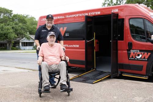 a bus driver pushes a man in a wheelchair