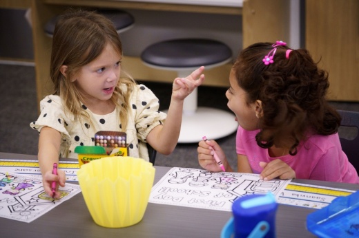 two young students talk to each other at a table