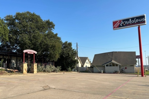 Exterior of a building lined with trees and a stand-alone sign reading Andalous Mediterranean Mezza.