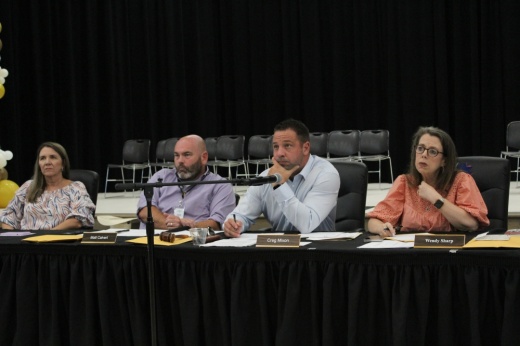 people sit in front of a black curtain and listen to a speaker at a meeting