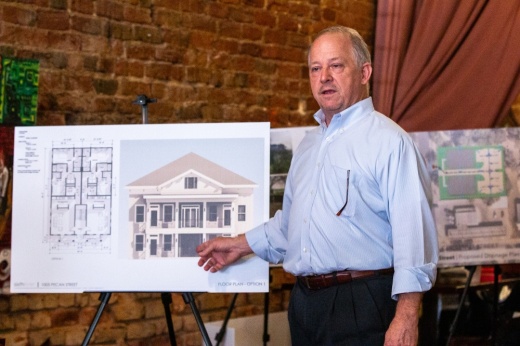 a man points a poster board showing a house
