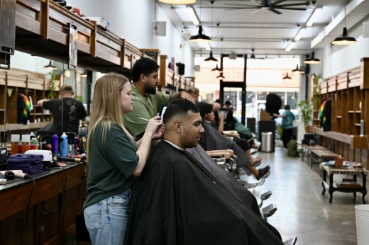a blonde woman cuts a mans hair