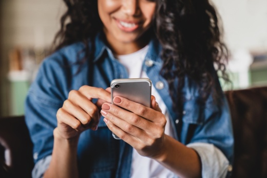 a woman smiles while using a smart phone