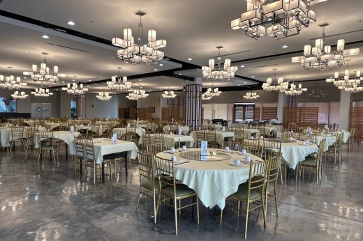 Interior of a restaurant's dining space featuring cloth tablecloth and modern chandeliers.