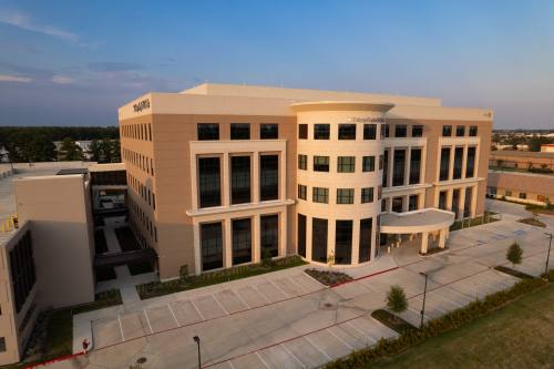 aerial view of a beige building with windows and a parking lot