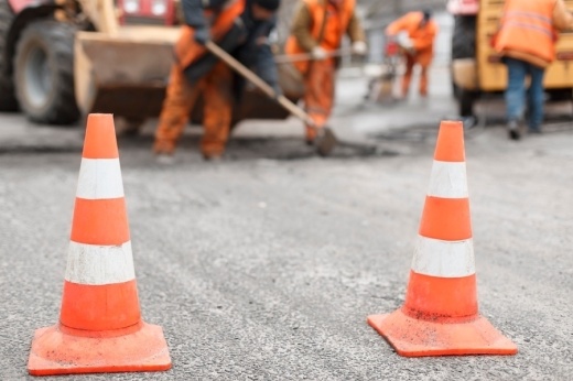 traffic cones in the road with workers in the background