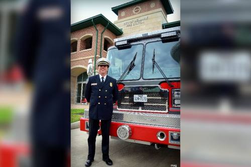 a man wearing a fire chief uniform next to a fire truck