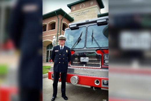 a man wearing a fire chief uniform next to a fire truck