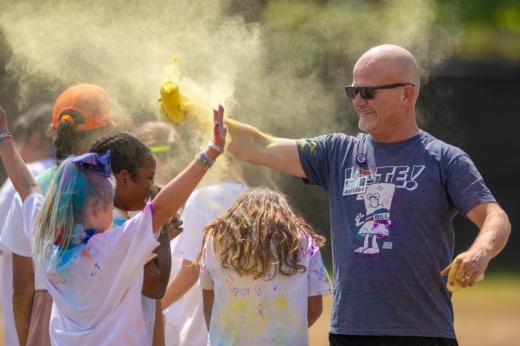 man participates in color spray event with children