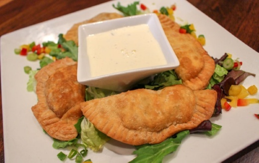 Empanadas Don Pedro are four Argentinian-style empanadas filled with chicken, beef, shrimp or vegetables and served with a basil cream sauce at Chimichurri's South American Grill. (Community Impact Staff)
