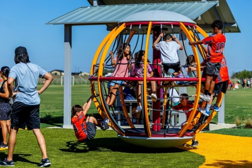 children play on a spherical playground installation at a park