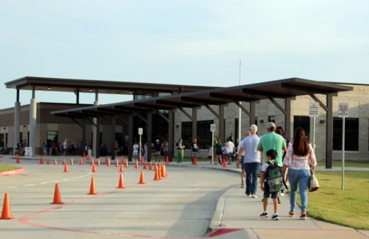 Students walking into a school with their parents