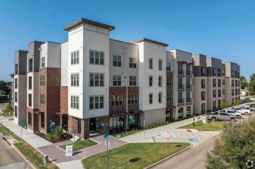 A white and brown apartment complex against a blue sky.