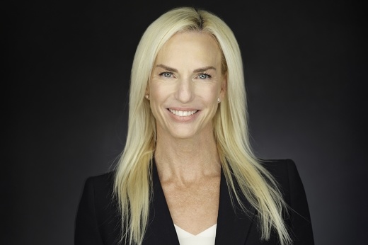 a blonde women wearing a black blazer against a black background