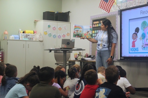 A teacher reads a book to elementary students