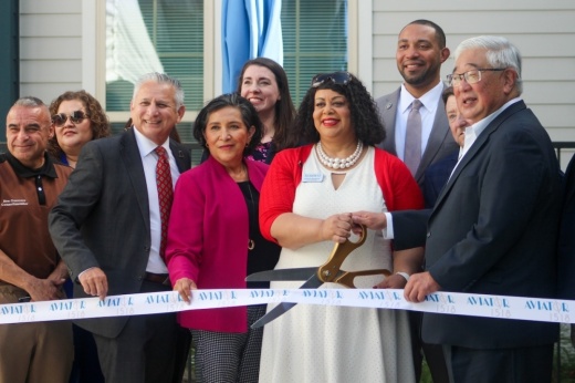 people in formal attire cut a ribbon with large scissors