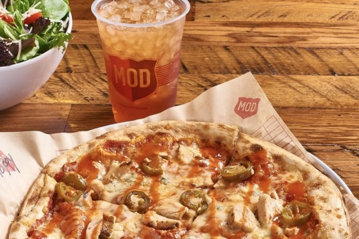 Pizza on a table next to a drink and a salad