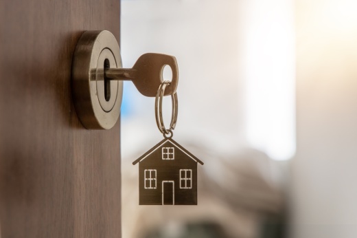 a key with a house keychain inserted in a door lock