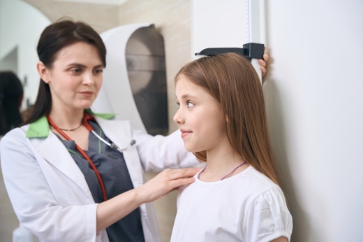 Qualified woman osteopath checking girl height and posture using special measurement tool, examining spine and bones quality, medical check-up