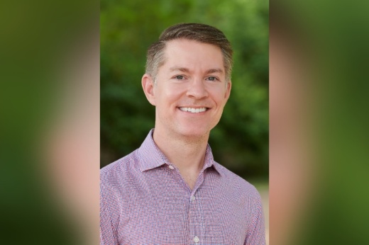 portrait headshot of a man wearing a red and blue checkered shirt