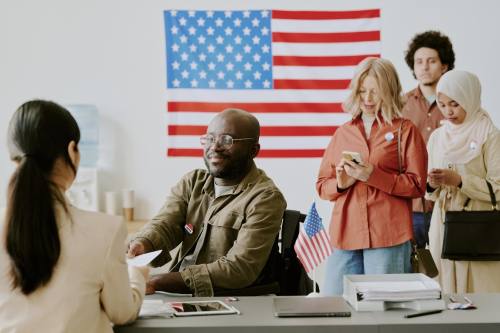 people at a voting location with the American flag in the background