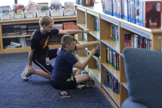 students look through books on a library shelf