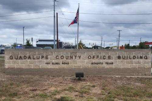 A sign for the Guadalupe County Office Building in Seguin, Texas is shown on a cloudy day.