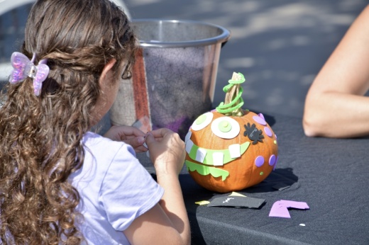 a girl decorates a small pumpkin