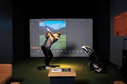 A man swinging a golf ball at a screen at a Back Nine golf simulator