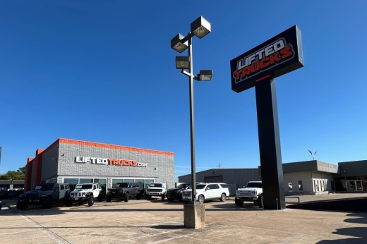 Exterior of a building featuring Lifted Trucks signage with a separate Lifted Trucks sign in the parking lot.