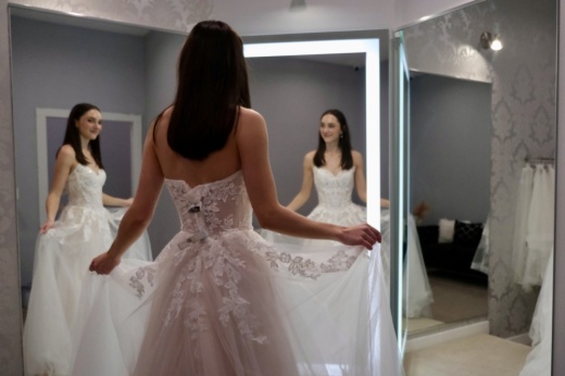 London Beal, assistant store manager and stylist at Coreena’s Bridal, showcases one of the dresses at the Georgetown boutique. (Gracie Warhurst/Community Impact)