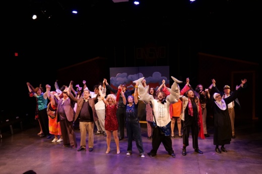 Group of people holding hands which are held above their heads while forming a circle.