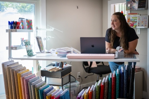 Trina Iblings, owner of Snippets, sits at her desk wating a hand stitching class take place.