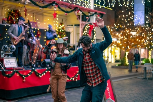 a person dances in front of a band with lights and Christmas decorations in the background