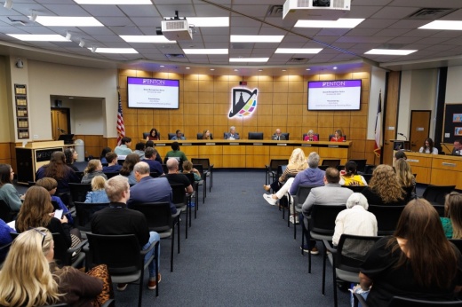 a group of people sit in a large board meeting room